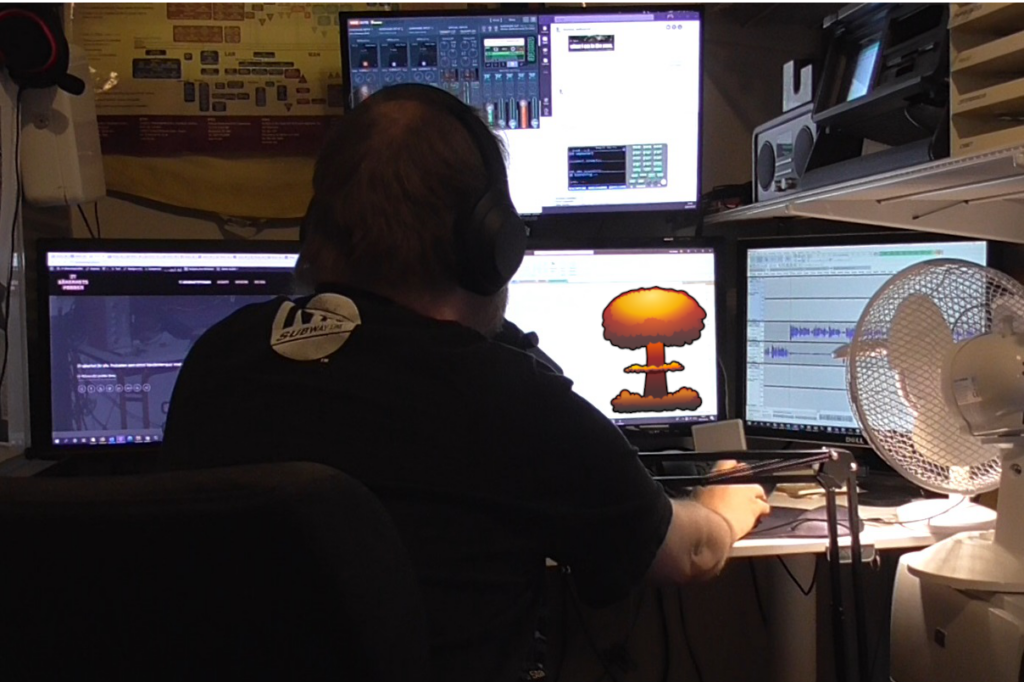 A picture of some guy (me) in front of a recording desk with a nuclear bomb on the screen.
